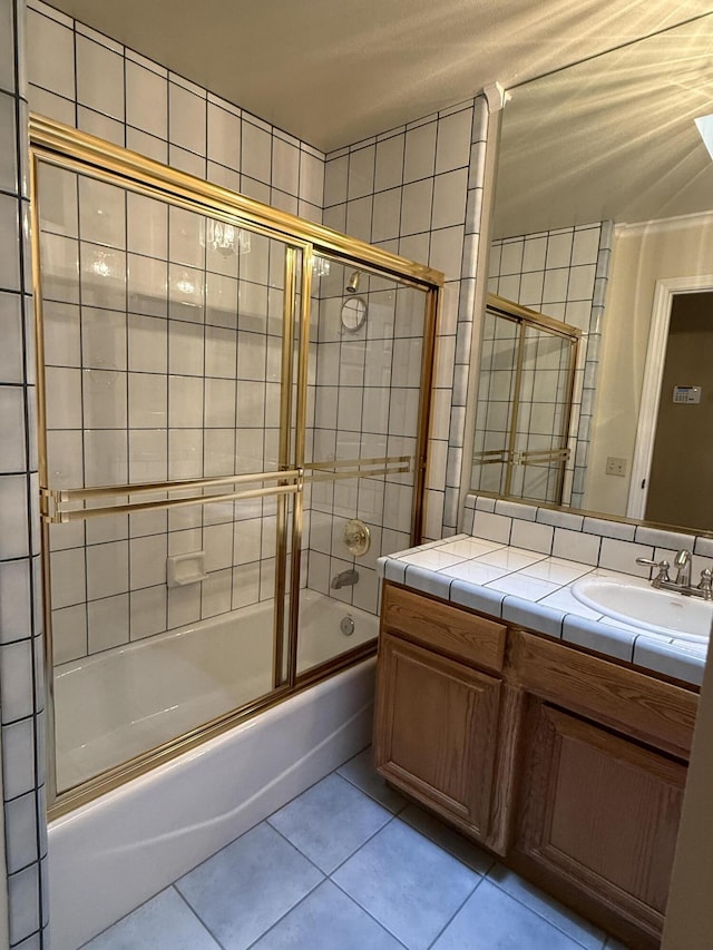 bathroom with vanity, combined bath / shower with glass door, tile patterned flooring, and tile walls