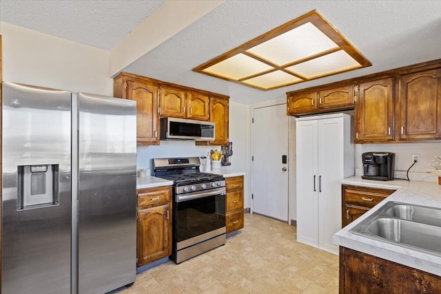 kitchen featuring sink, a textured ceiling, and appliances with stainless steel finishes