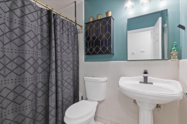 bathroom with tile walls, curtained shower, and toilet