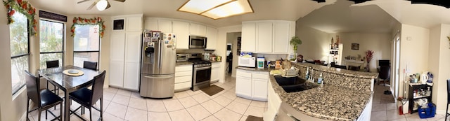 kitchen with appliances with stainless steel finishes, a ceiling fan, white cabinets, light tile patterned flooring, and a sink