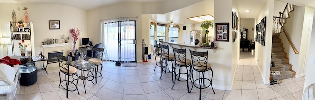 interior space featuring stairs, baseboards, a glass covered fireplace, and tile patterned floors