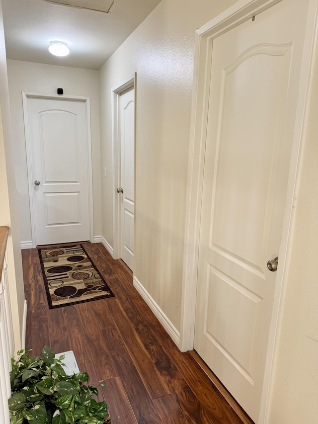 hall featuring baseboards and dark wood-type flooring