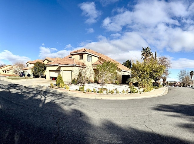 mediterranean / spanish house with driveway, an attached garage, a tile roof, and stucco siding