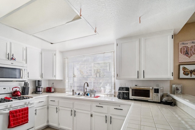 kitchen featuring a toaster, white cabinets, a sink, a textured ceiling, and white appliances