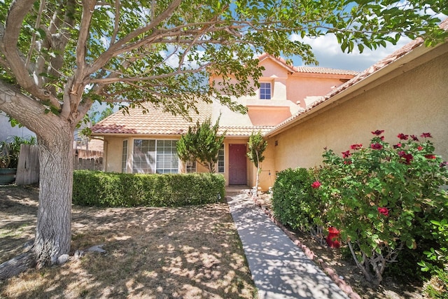 view of front facade featuring a tile roof, fence, and stucco siding