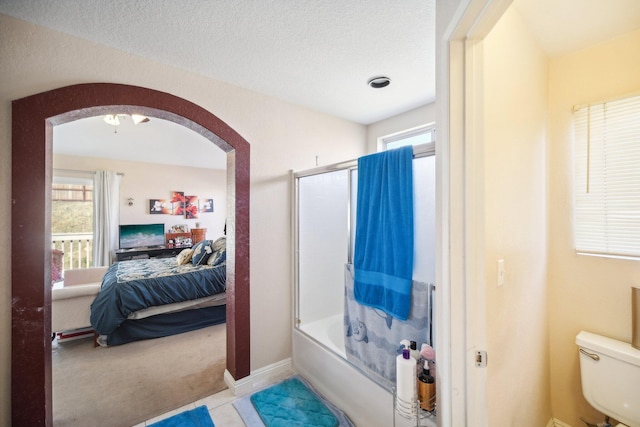 bathroom with tile patterned flooring, toilet, and shower / bath combination with glass door