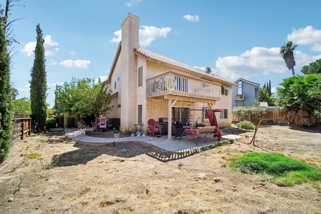 rear view of house with a patio, a chimney, stucco siding, a balcony, and a fenced backyard