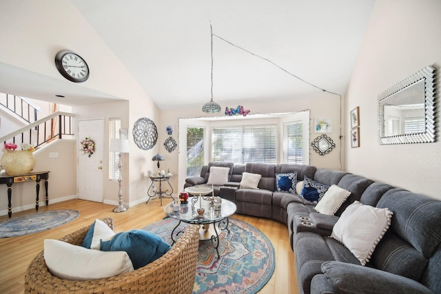 living room featuring high vaulted ceiling, stairs, baseboards, and wood finished floors