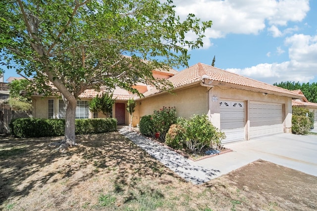 view of front of home with a garage, concrete driveway, a tiled roof, and stucco siding