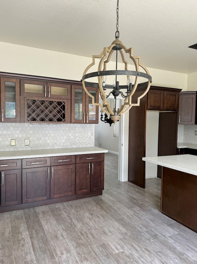 5604 Kingman Dr, Palmdale, CA 93552 - kitchen featuring a chandelier, light countertops, dark brown cabinetry, tasteful backsplash, and a textured ceiling