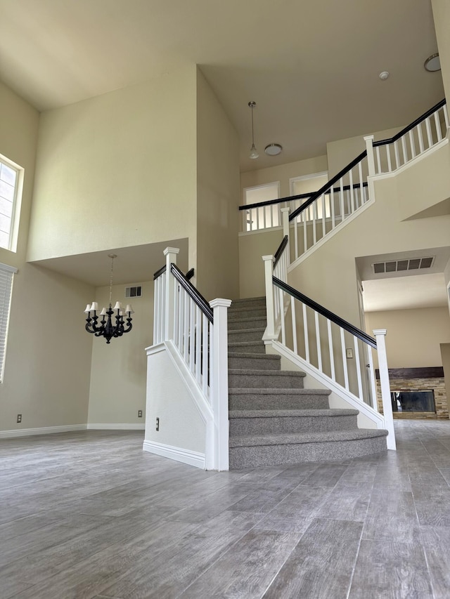 5604 Kingman Dr, Palmdale, CA 93552 - stairs with a high ceiling, a stone fireplace, a chandelier, wood finished floors, and baseboards