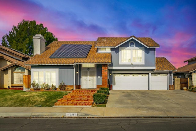 view of front of home featuring solar panels, a yard, and a garage