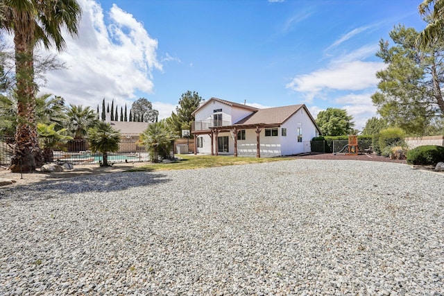 view of front of property featuring a playground, fence, and stucco siding