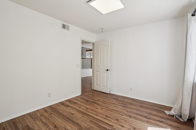 spare room with visible vents, baseboards, and wood finished floors