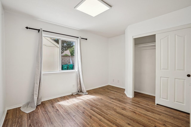 unfurnished bedroom with baseboards, a closet, and wood finished floors
