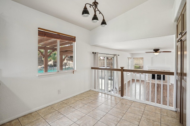 empty room with light tile patterned floors, baseboards, a ceiling fan, and lofted ceiling