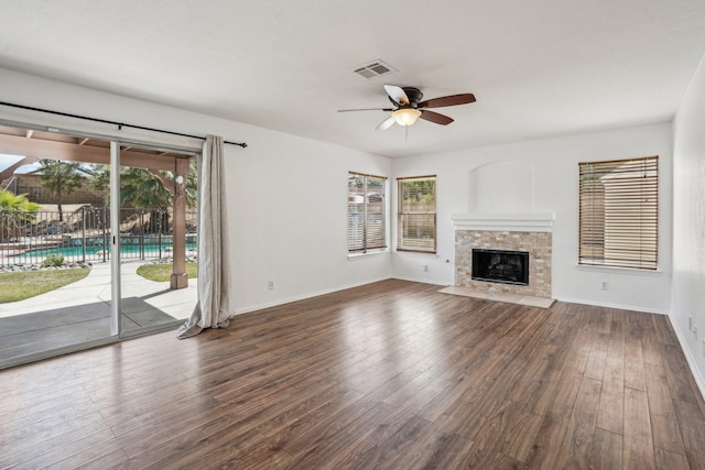unfurnished living room with a ceiling fan, visible vents, a fireplace with flush hearth, wood finished floors, and baseboards