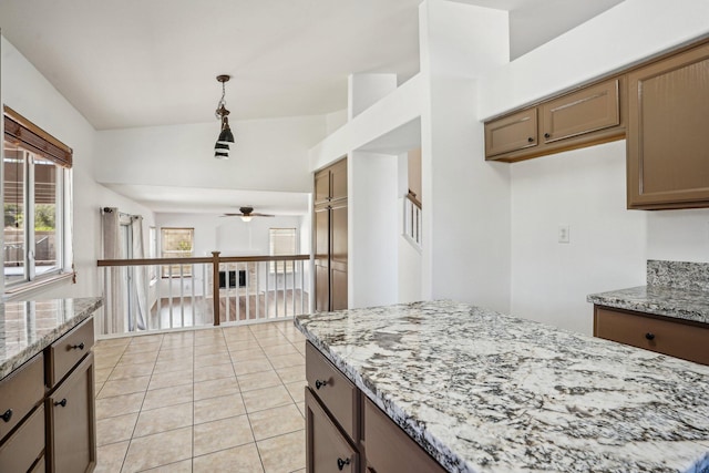 kitchen with light tile patterned flooring, light stone countertops, ceiling fan, vaulted ceiling, and hanging light fixtures