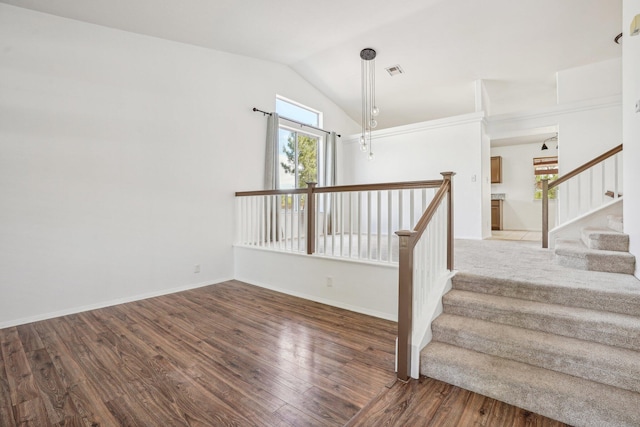 stairway featuring baseboards, visible vents, wood finished floors, and vaulted ceiling
