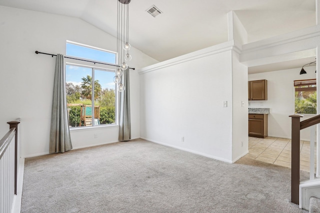 unfurnished room featuring visible vents, lofted ceiling, a wealth of natural light, and light carpet