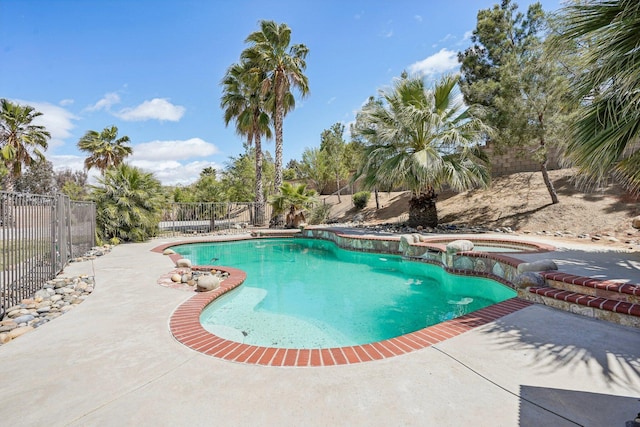 view of pool with a fenced in pool, fence, an in ground hot tub, and a patio area