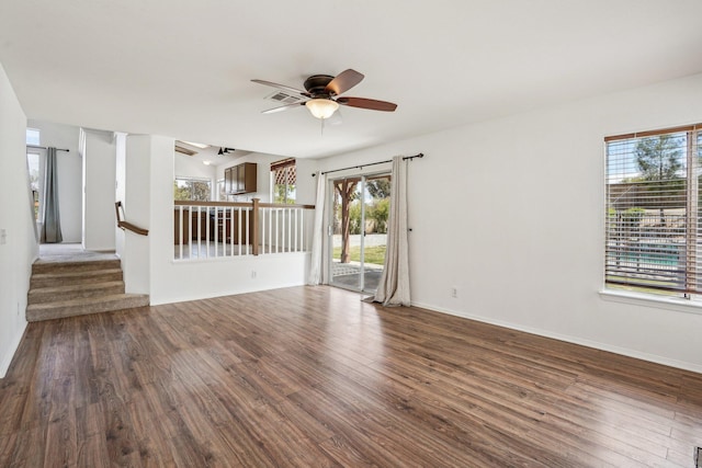 unfurnished living room featuring a ceiling fan, wood finished floors, a healthy amount of sunlight, and stairway