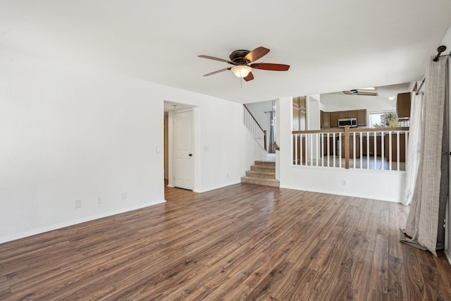 unfurnished living room with baseboards, stairs, ceiling fan, and wood finished floors