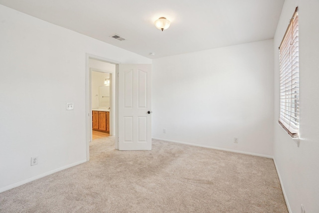 empty room with baseboards, light colored carpet, and visible vents