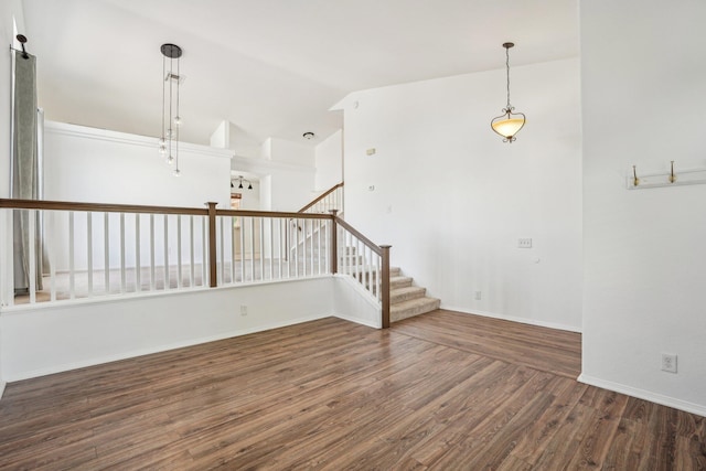 empty room featuring baseboards, stairs, lofted ceiling, and wood finished floors