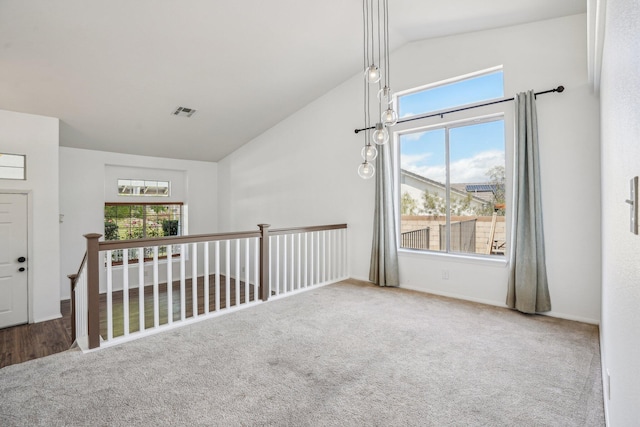 empty room with baseboards, carpet, high vaulted ceiling, and visible vents