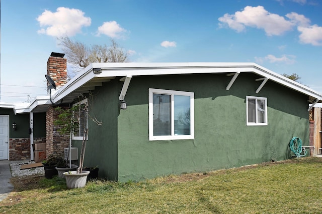 44128 Stanridge Ave, Lancaster, CA 93535 - view of side of home with a chimney, stucco siding, and a yard
