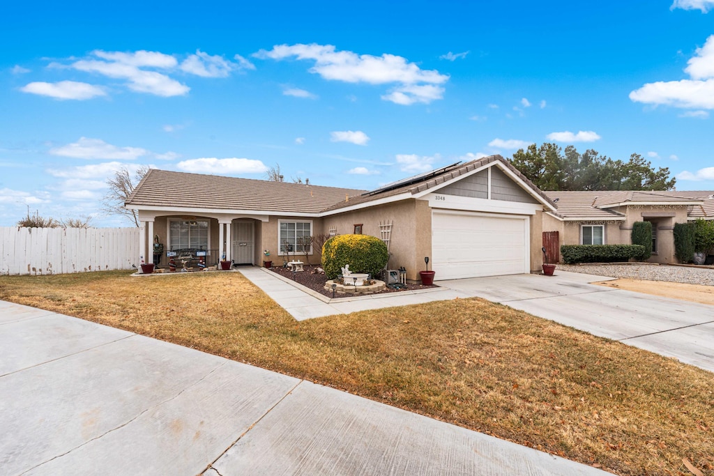 ranch-style home featuring a garage, a front lawn, covered porch, and solar panels