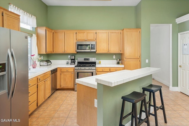 36525 Summerholly Cir, Palmdale, CA 93550 - kitchen featuring appliances with stainless steel finishes, tile countertops, light tile patterned flooring, a center island, and a towering ceiling