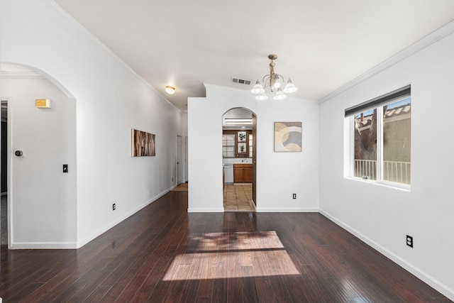 spare room featuring dark hardwood / wood-style flooring, crown molding, and a chandelier