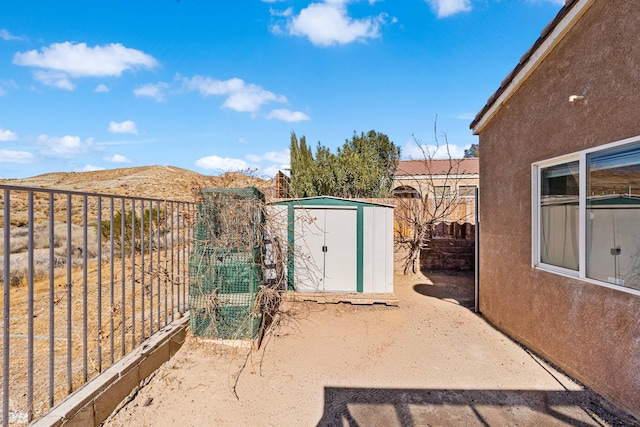 view of gate with a mountain view and a shed