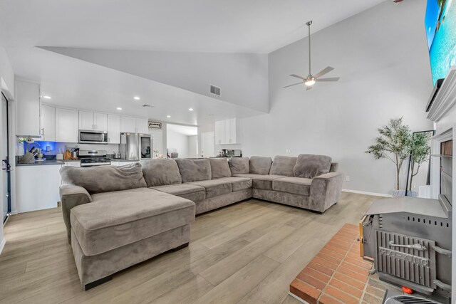 living room with ceiling fan, high vaulted ceiling, and light hardwood / wood-style floors