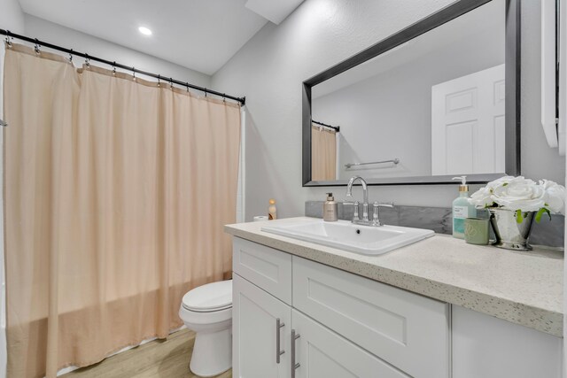 full bathroom with hardwood / wood-style floors, vanity, toilet, and shower / tub combo