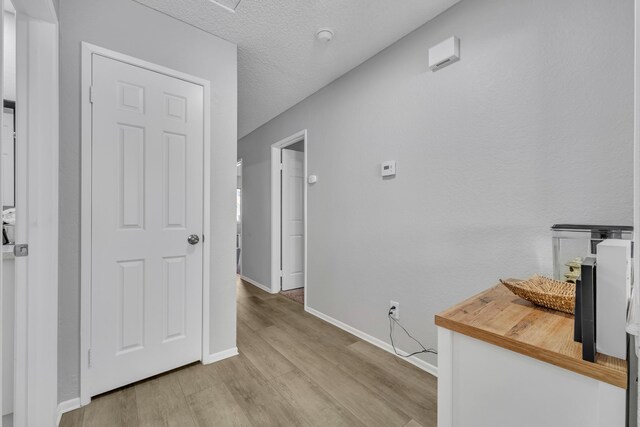 hall with a textured ceiling and light wood-type flooring