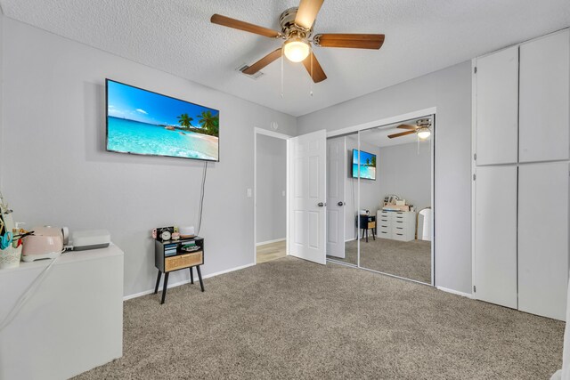 bedroom with a textured ceiling, ceiling fan, light carpet, and a closet