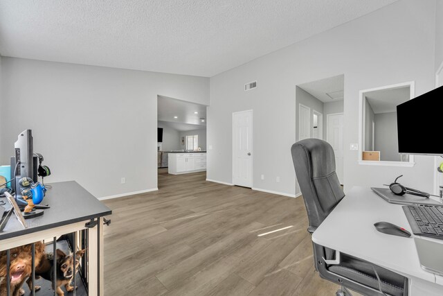 office area featuring wood-type flooring, a textured ceiling, and vaulted ceiling