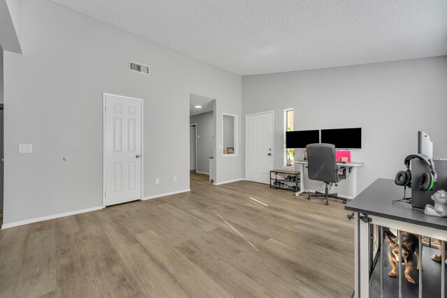 unfurnished office with hardwood / wood-style floors, a textured ceiling, and high vaulted ceiling