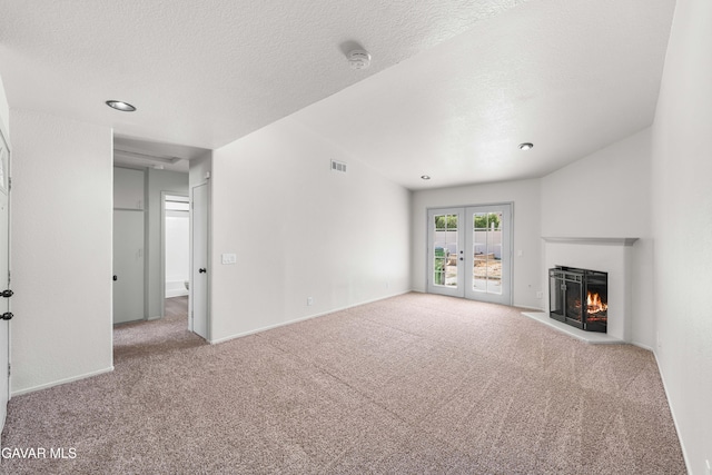 37632 E 15th St, Palmdale, CA 93550 - unfurnished living room with carpet floors, french doors, a warm lit fireplace, and a textured ceiling