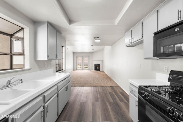 37632 E 15th St, Palmdale, CA 93550 - kitchen featuring black appliances, dark wood-style flooring, open floor plan, a raised ceiling, and gray cabinetry