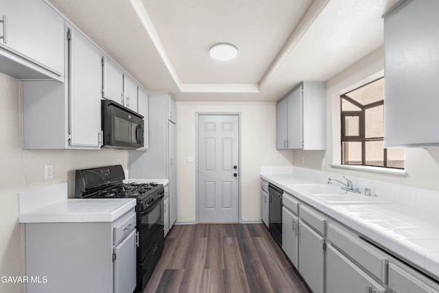 37632 E 15th St, Palmdale, CA 93550 - kitchen featuring black appliances, tile counters, dark wood-type flooring, and a raised ceiling
