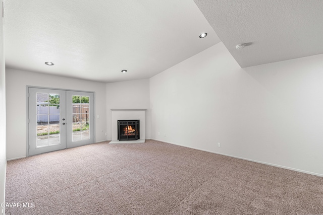 37632 E 15th St, Palmdale, CA 93550 - unfurnished living room with carpet flooring, french doors, a textured ceiling, a warm lit fireplace, and recessed lighting