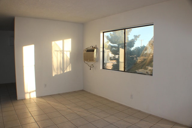 unfurnished room with an AC wall unit and light tile patterned flooring