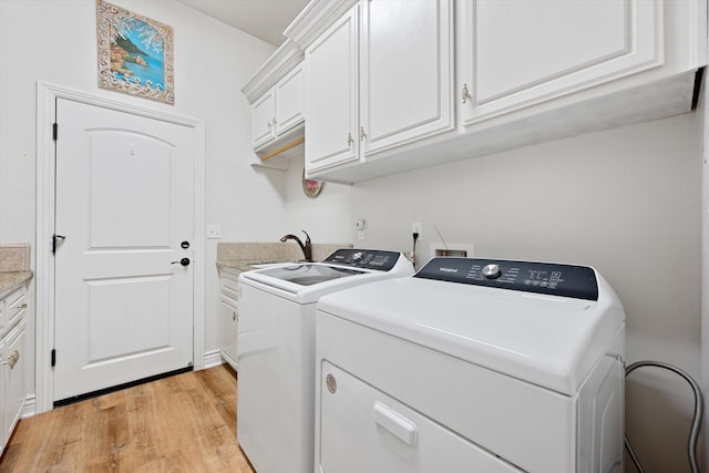 clothes washing area featuring cabinets, separate washer and dryer, and light hardwood / wood-style flooring