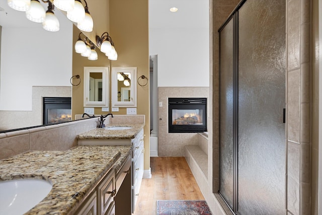 bathroom with a fireplace, vanity, wood-type flooring, and shower with separate bathtub