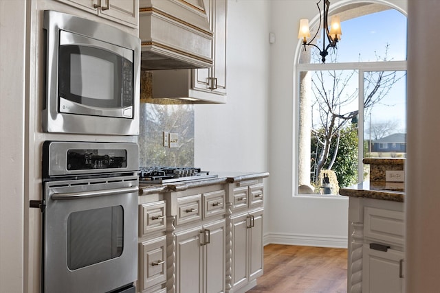 kitchen featuring premium range hood, a wealth of natural light, a chandelier, and stainless steel appliances