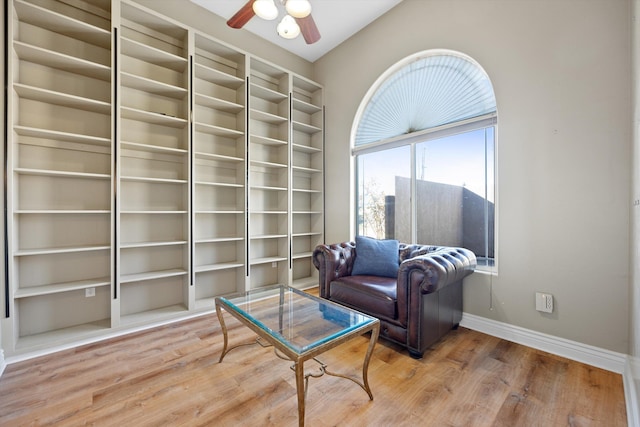 living area with built in shelves, ceiling fan, and hardwood / wood-style flooring